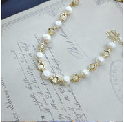 Gullfarget armbånd med hvite perler