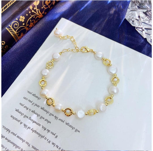 Gullfarget armbånd med hvite perler