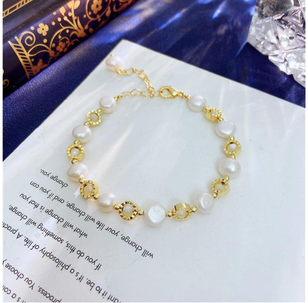 Gullfarget armbånd med hvite perler