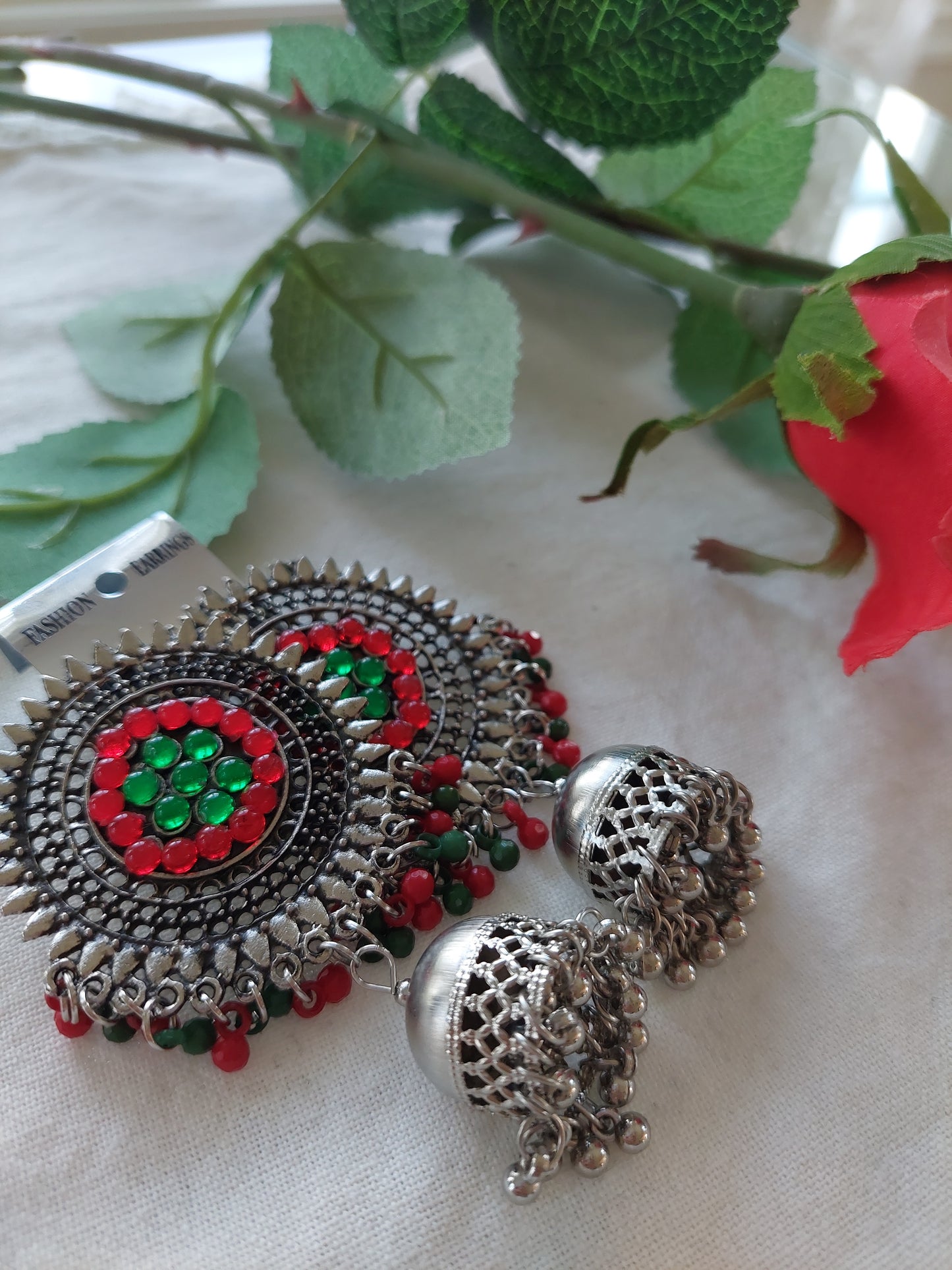 Sølvfarget ørepynt med dataljer i rødt