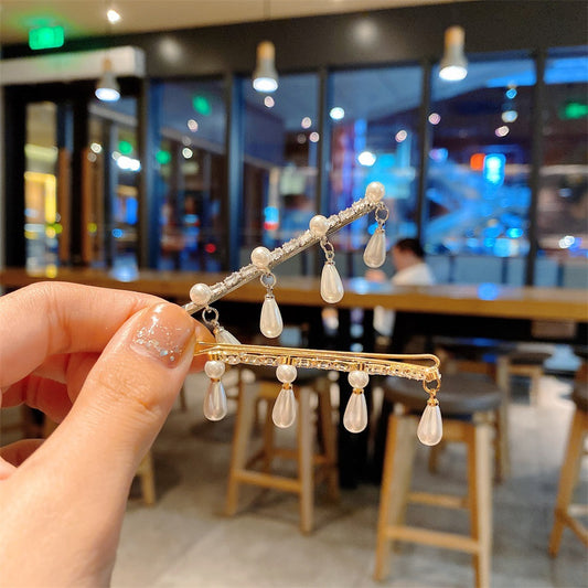 Hårspenne i gull og sølvfarge med hengende perler